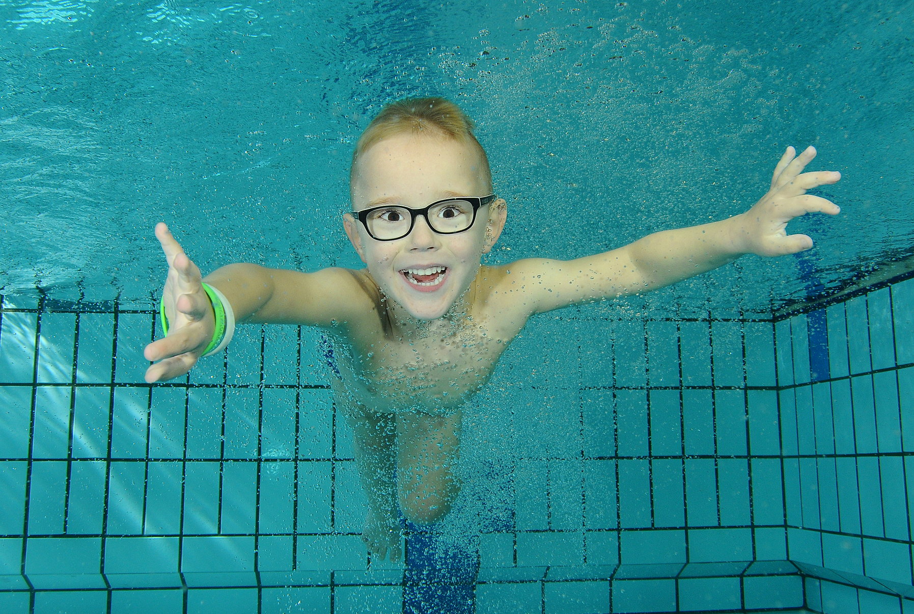 Junior Club-lid duikt met open armen onder water in het wedstrijdbad